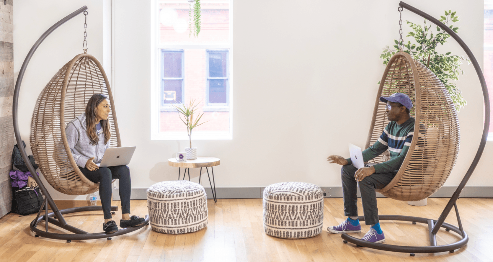 Two employees sitting in hanging chairs having a career conversation.