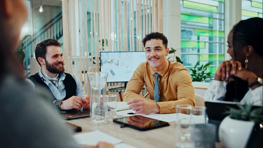Colleagues having a friendly discussion around a table in a modern office.