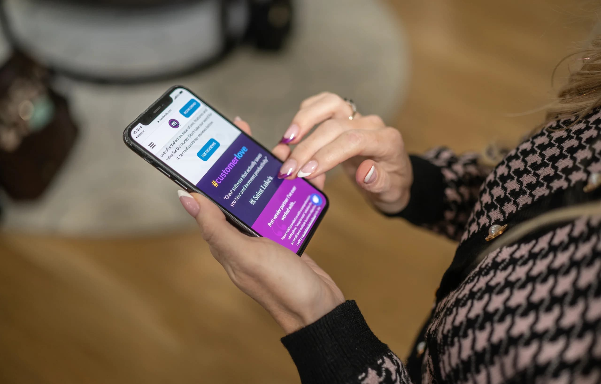 Close-up of a woman's hands holding a smartphone with a social media customer service app open, displaying a conversation and hashtags related to customer feedback.