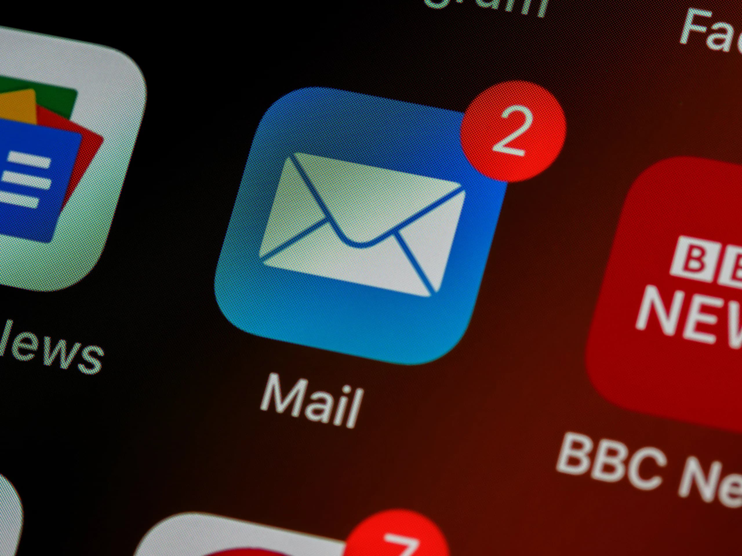 Close-up view of a smartphone screen displaying various app icons, with focus on the Mail app icon that shows two unread messages.