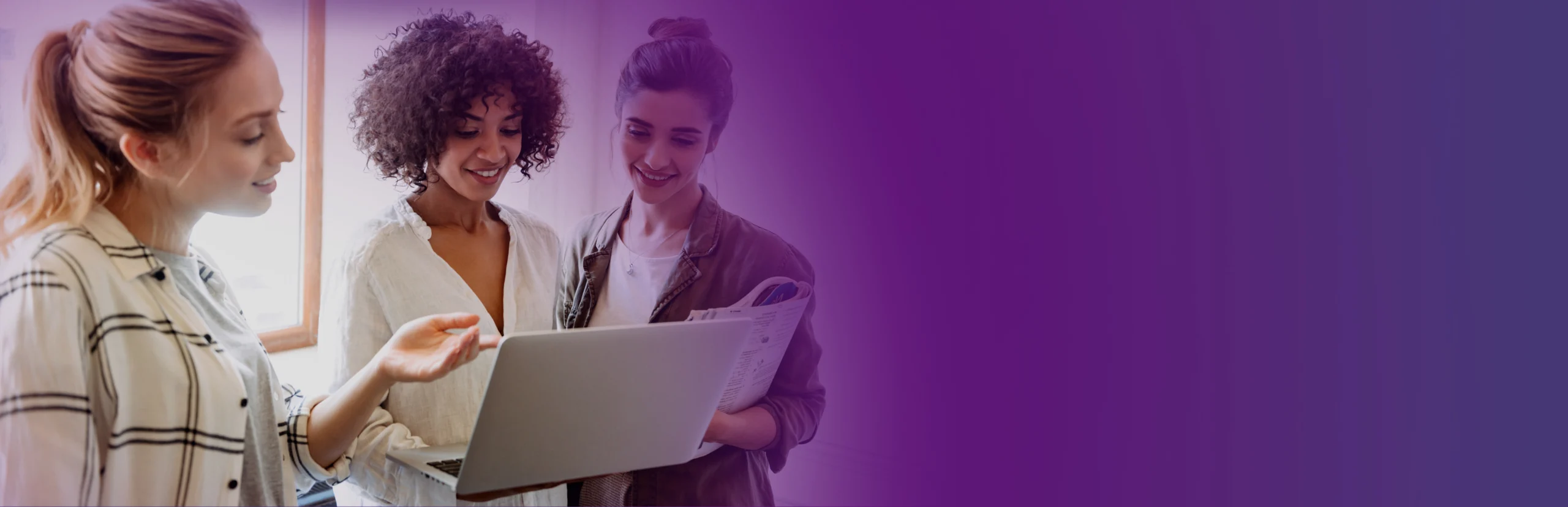 Three professional women closely examining a document on a laptop, actively engaging in a discussion, with a vibrant purple gradient background enhancing the focused atmosphere.