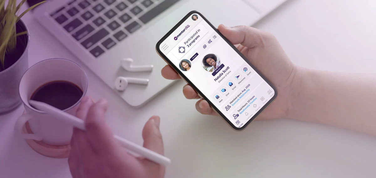 Hand holding smartphone with the MentorcliQ app