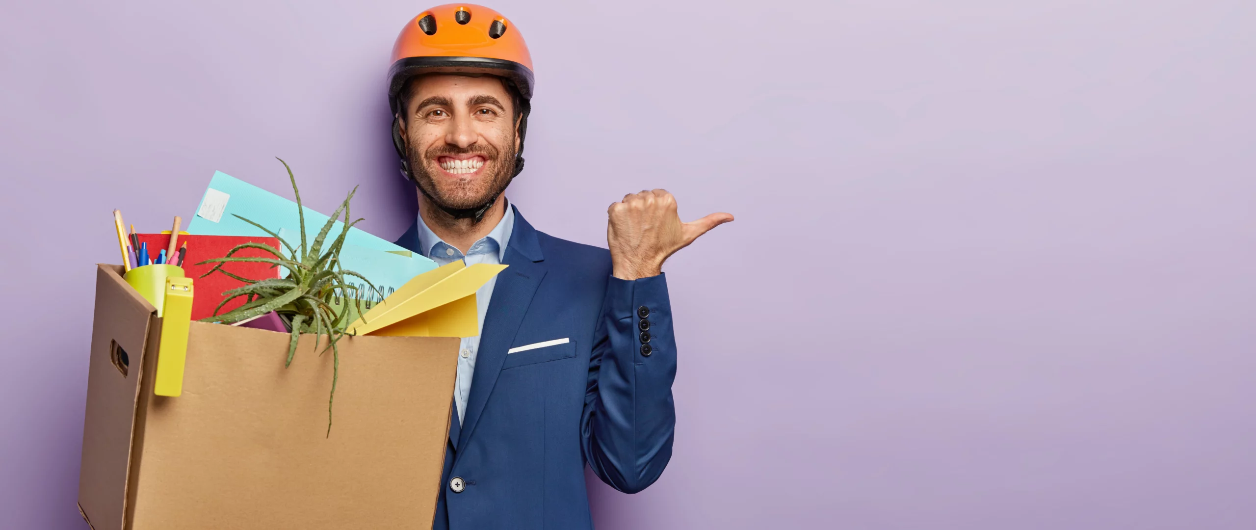 A man in a suit with his personal items inside a box, happy, because of his Mentoring for Onboarding Success