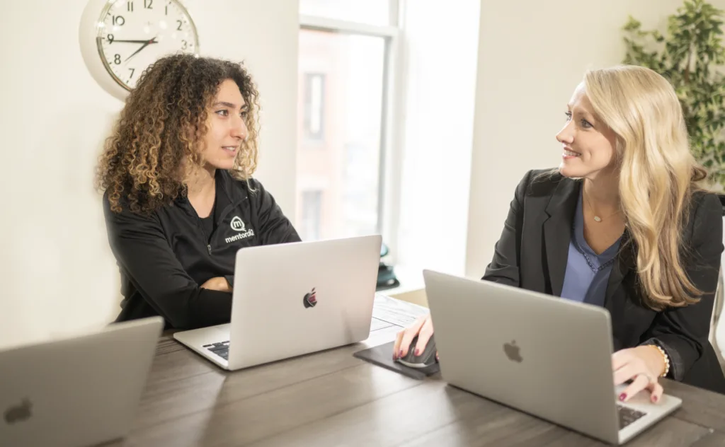 Peer Mentor Programs: How They Work and How to Start Them 9 Two women talking at a table when peer mentoring.