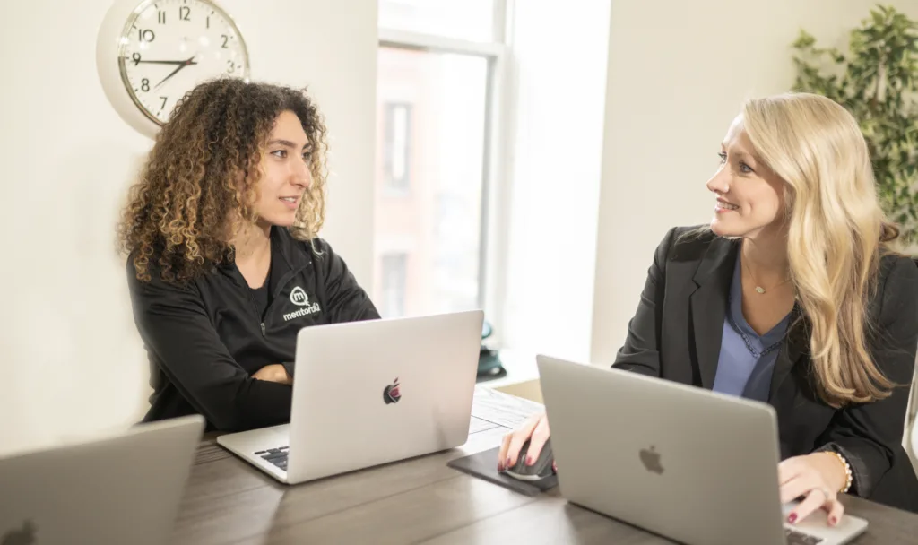 Women in an office setting goals for improving mentoring program engagement.