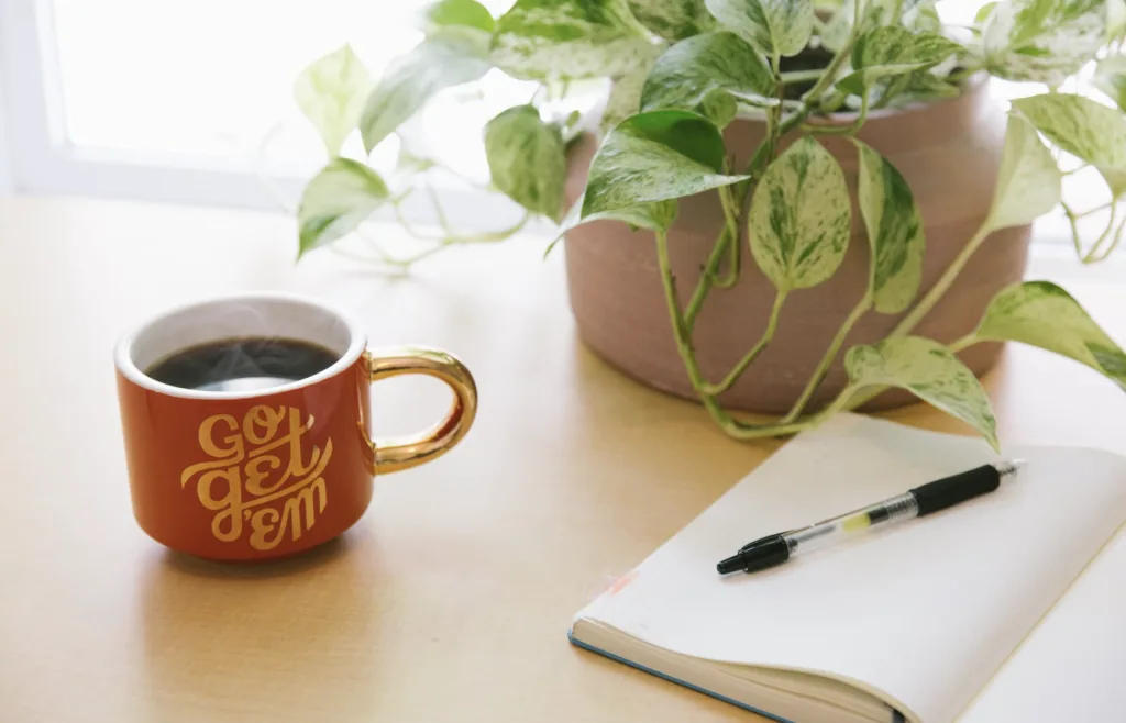 Go Get'em coffee mug with a gratitude journal on an office desk