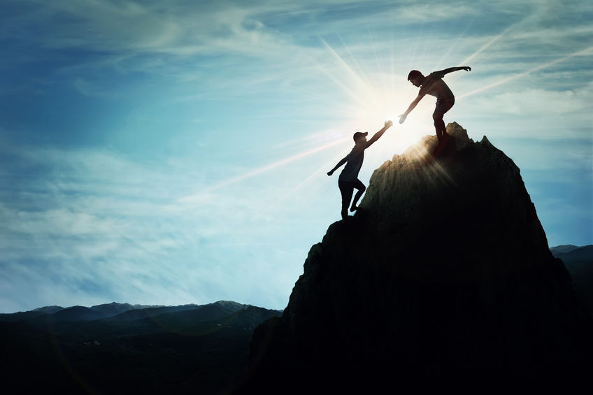 Silhouette of helping hand between two people climbing a rock, A friendly hand on the high mountain hike. inspirational teamwork. 