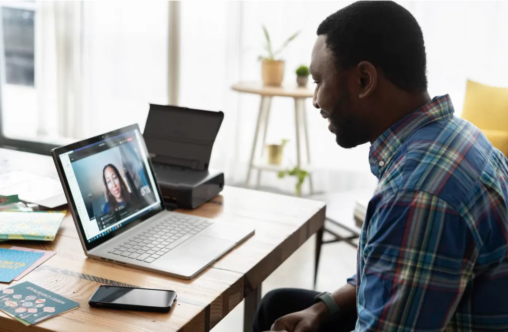 A man practicing how to be an effective mentor by having a conversation with a mentee on a video call. 