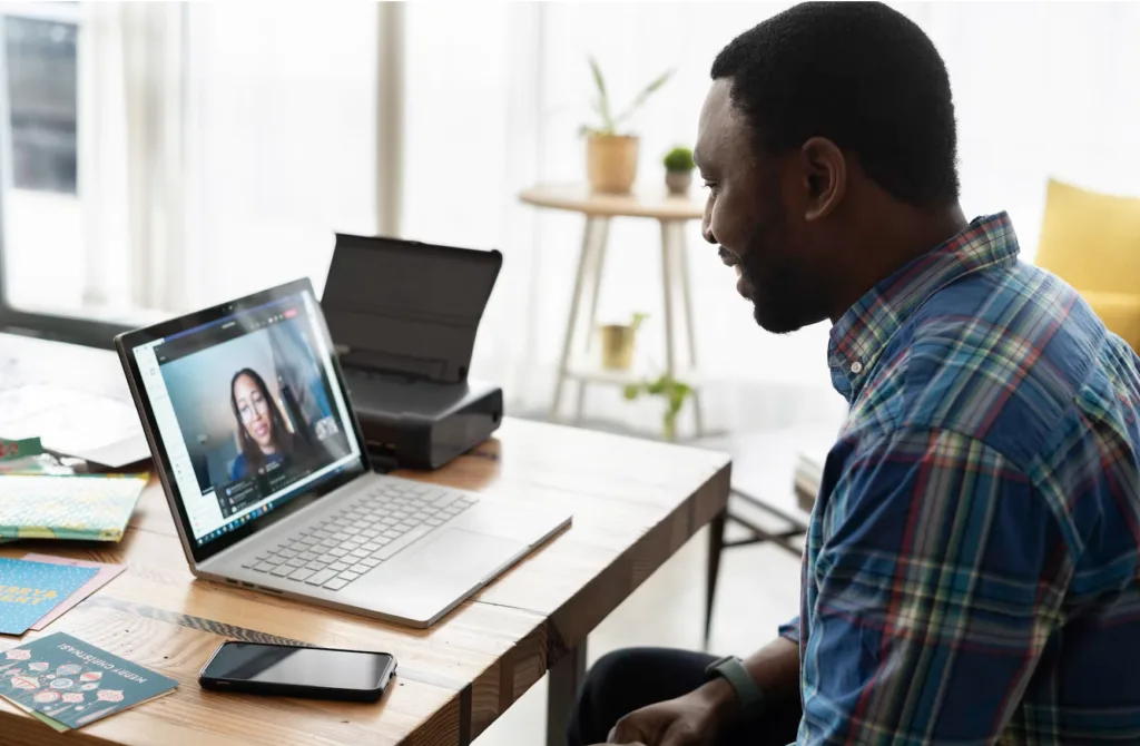 Man sitting at a computer talking on a zoom call as a virtual mentor.