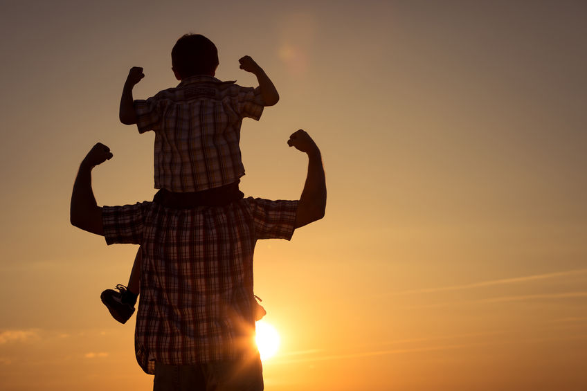 Father and son walking on the field at the sunset time. concept of family strength 