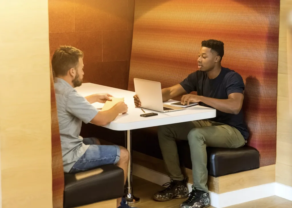 5 Ways to Make Mentoring a Personalized Learning Experience 4 A mentor and mentee sitting at table in an office booth discussing mentoring goals.