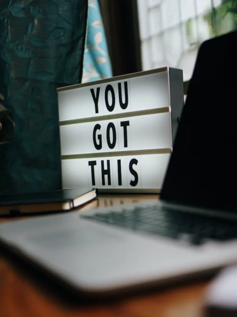 A light up sign on an office desk that says You Got This next to a laptop.