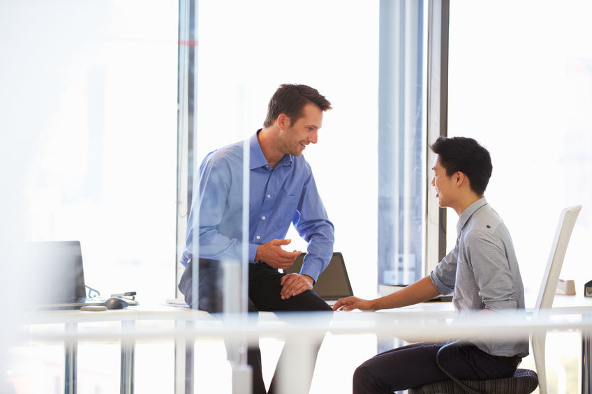 A mentor and mentee talking in a modern office.