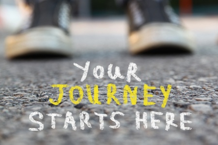image with selective focus over asphalt road and person with handwritten text - your journey starts here. 