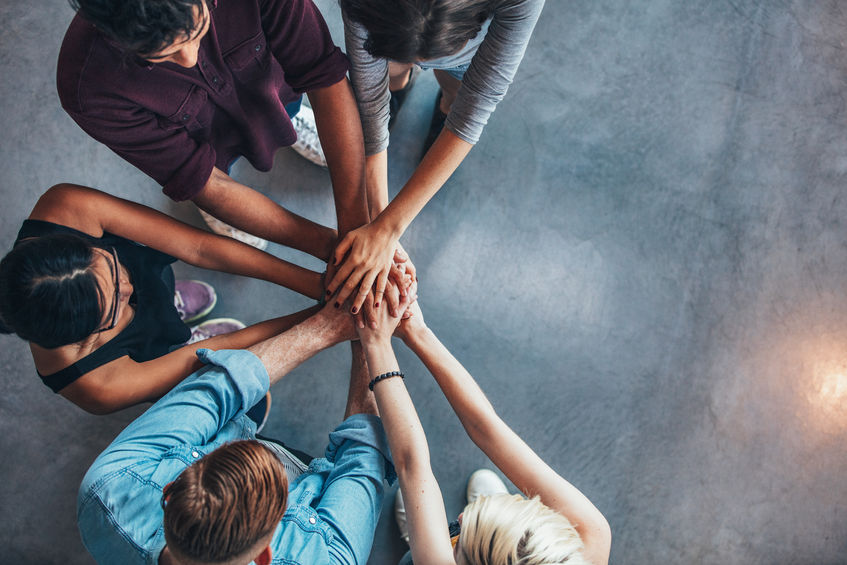 Top view of mentors and mentees putting their hands on top of each other in support.