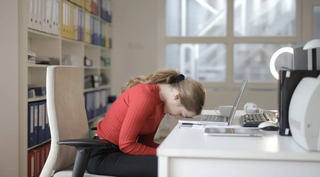 A worker gives up and puts her head on the computer, a reflection of the lack of employee recognition. 