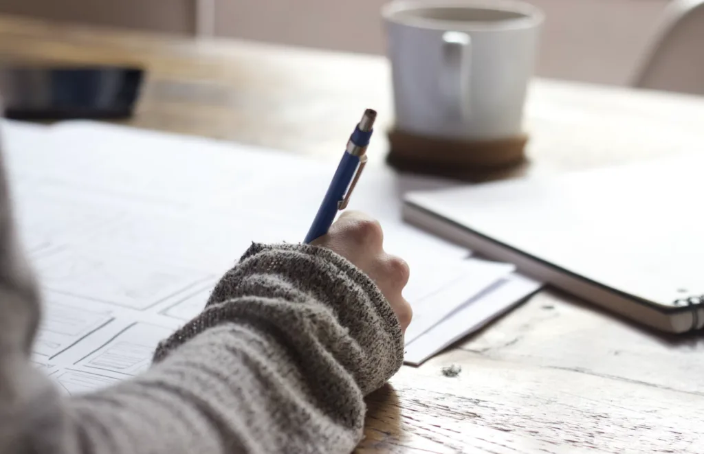 Woman writing down goals on a paper for her sales mentorship program.