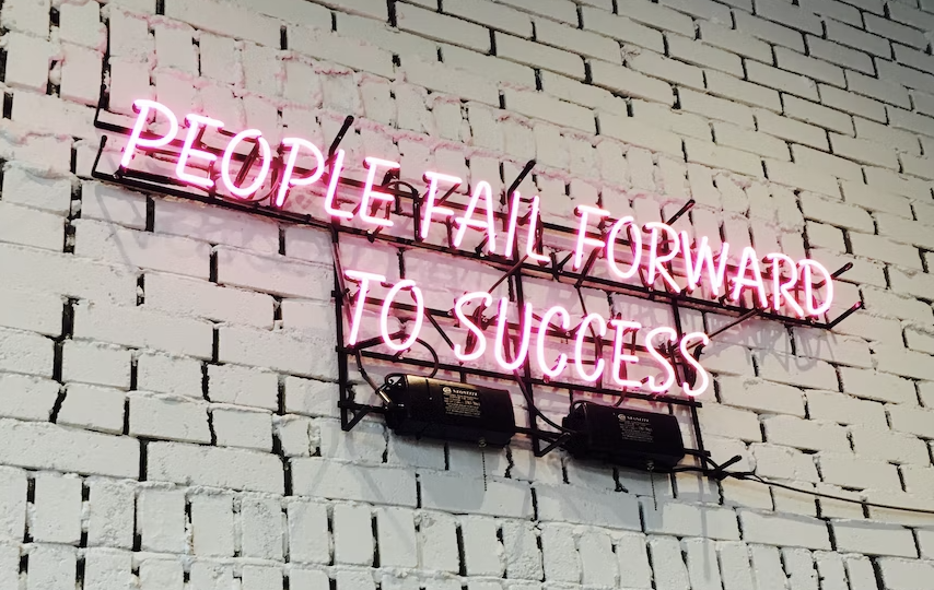 Neon sign that says People fail forward to success.