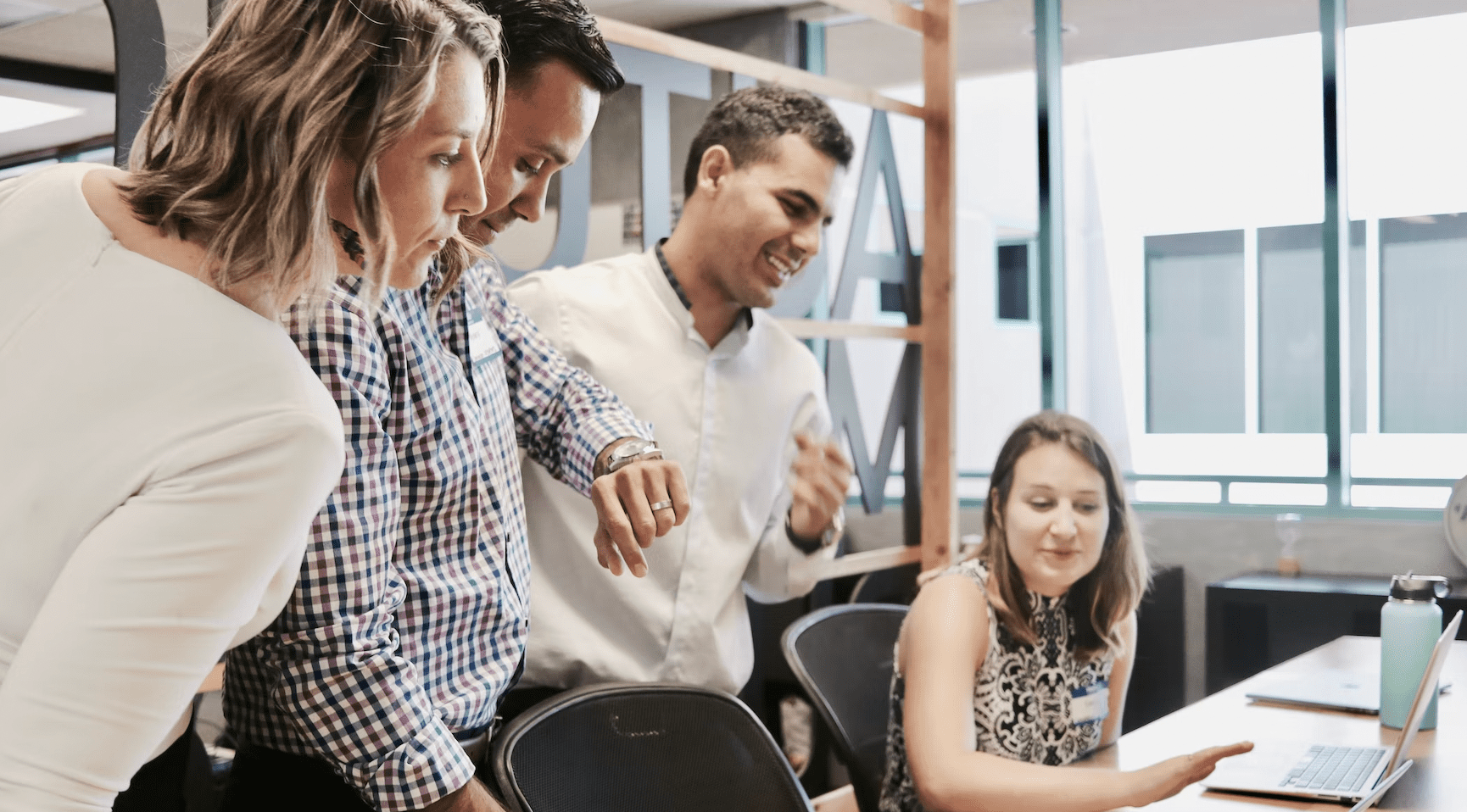 Employees in an office around a computer discussing engagement.