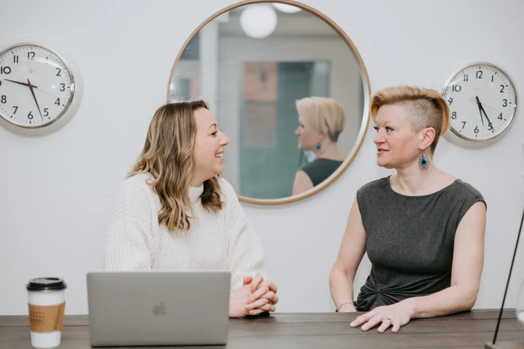 Two women at a table in an office discussing future mentor meetings. 