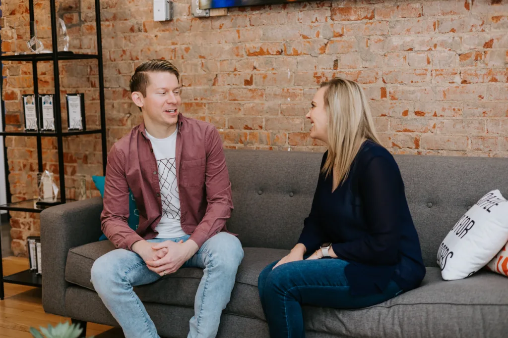 Man and women interviewing on a coach about performance goals.