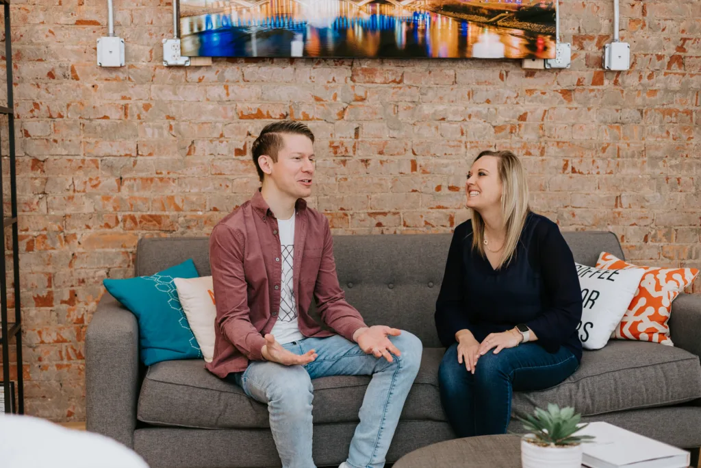 Man and woman sitting on a couch engaging in a leadership program discussion.