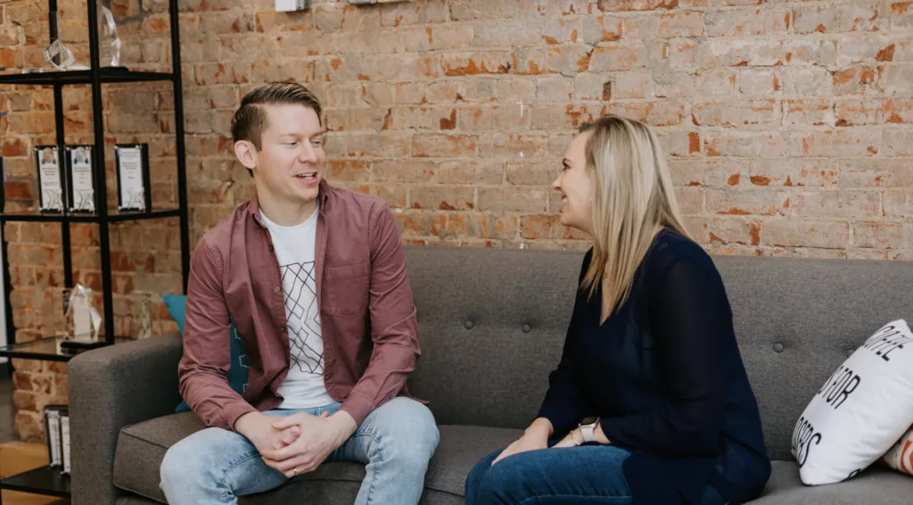 A man and a woman engage in conversation in an office setting. 