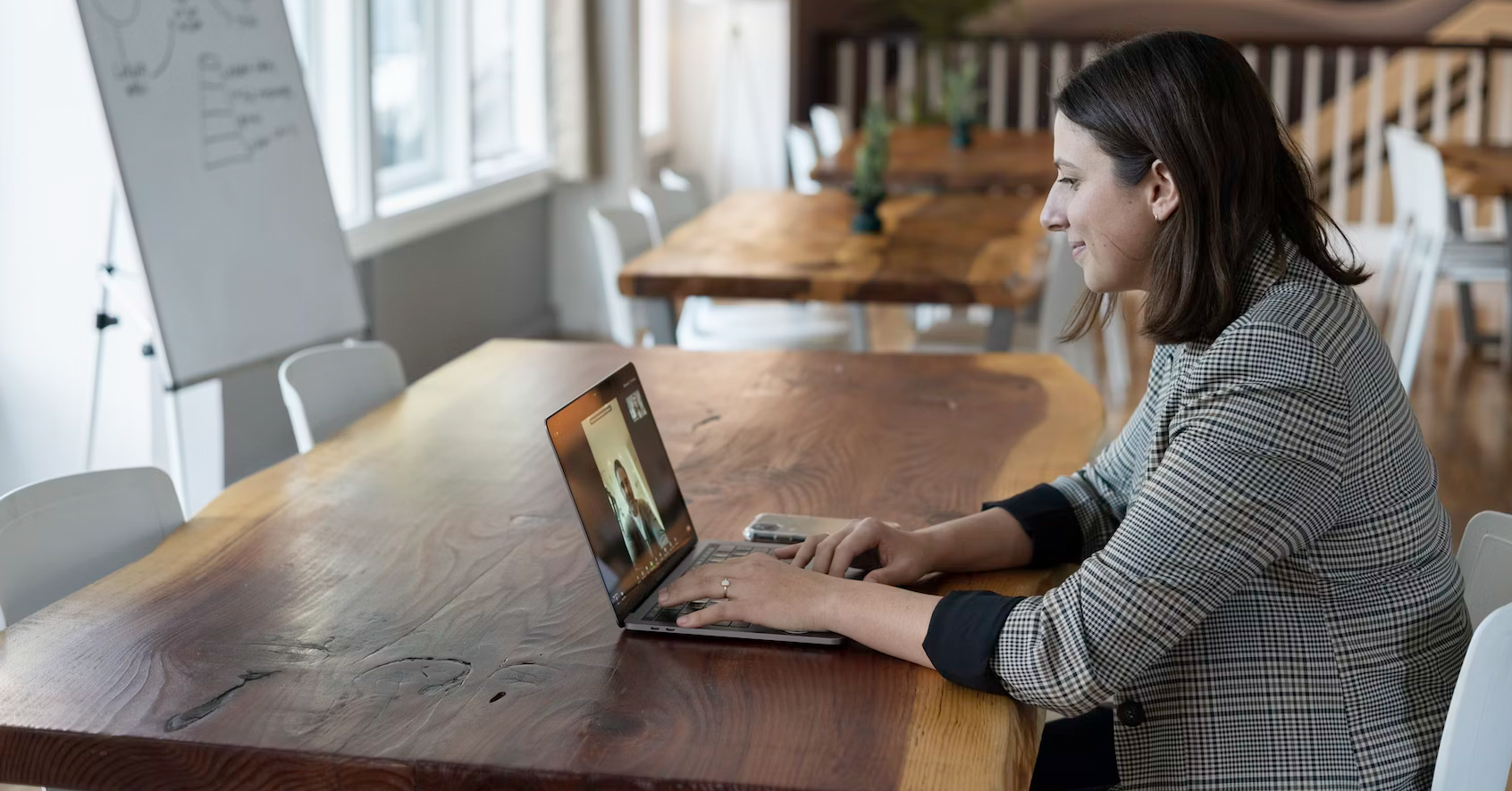 Worker sitting at a long table on a remote mentoring video call.