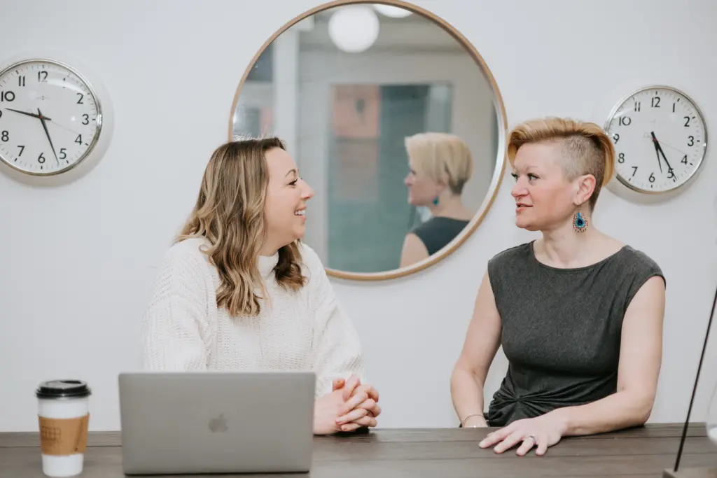 Performance Coaching at Work: What, Why, and How to Do It in the Workplace 6 Two women sitting at a table in deep discussion about performance mentoring.