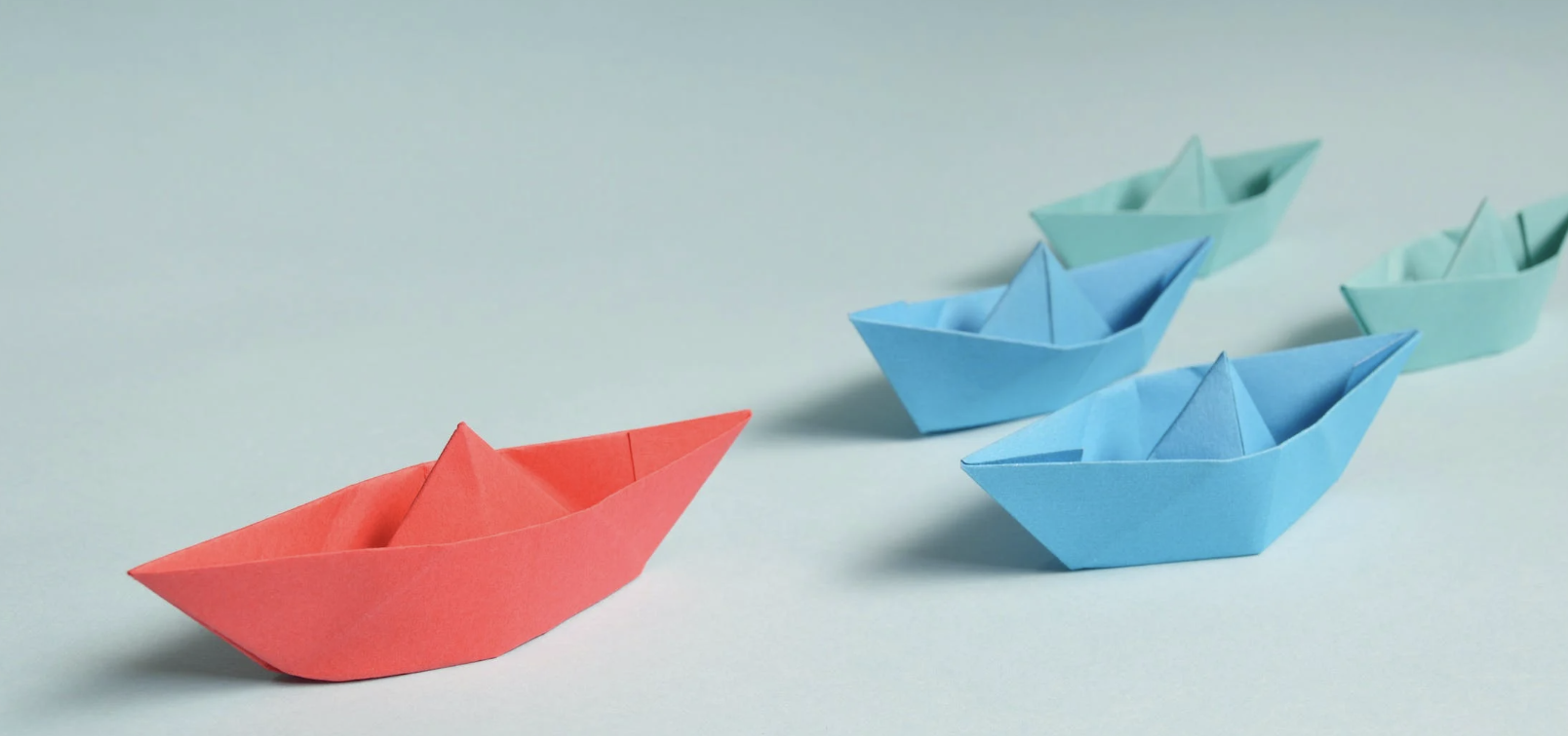 Definition of leadership represented by paper boats flowing behind a leader.