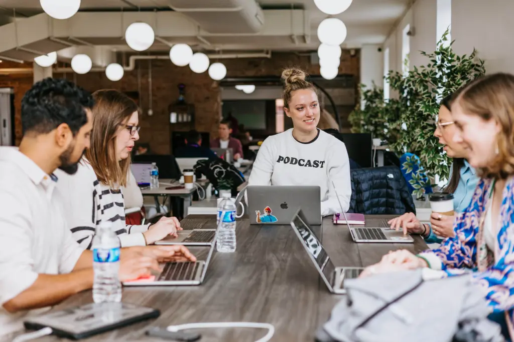 How to Reduce High Employee Turnover + Free Turnover Calculator 10 An image of happy employees sitting at a table together.