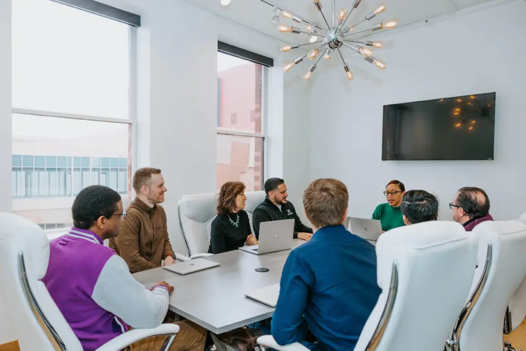 A group mentoring session happening in a large office board room. 