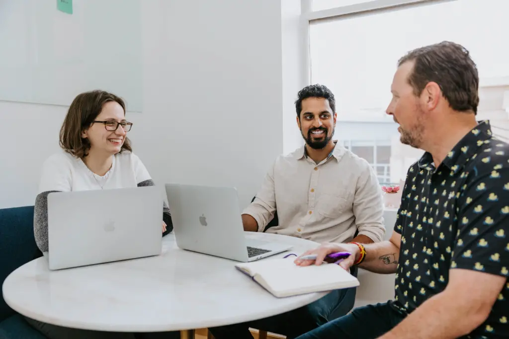 Three workers in an office discussing leadership styles.