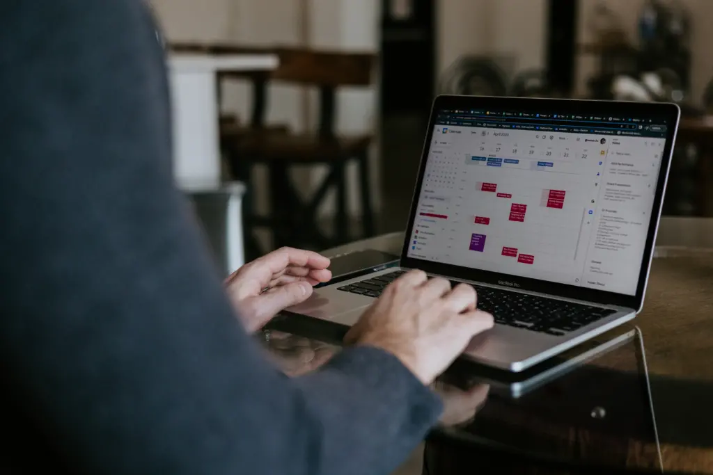 Image of a leader sitting at a computer with a calendar exhibiting strong operations leadership skills. 