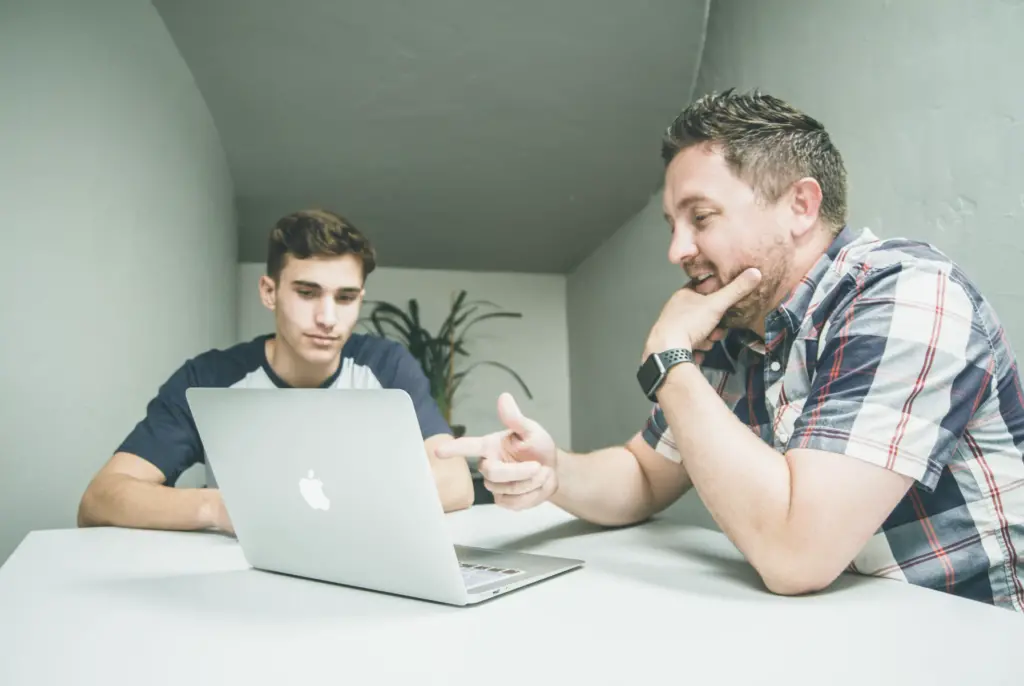 Father and son sit at a table discussing succession for their family owned business.