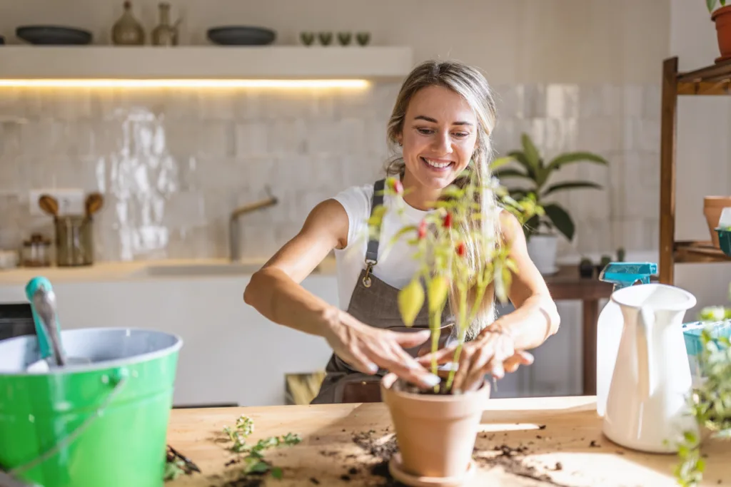 Photo of a happy young woman potting plants at home